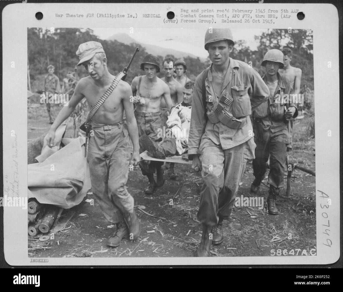 Un homme de la 11th Airborne Division sur l'île Leyte aux Philippines, est transporté à l'hôpital où son bras brisé sera traité. Banque D'Images