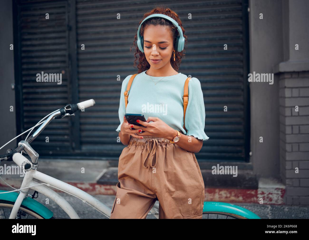 Téléphone, musique et femme noire vélo avec un vélo dans la ville d'Australie pour Voyage, aventure et pour se détendre. Jeune fille, urbaine et africaine sur social Banque D'Images