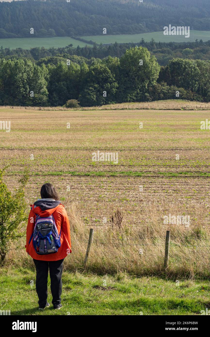 Fille en manteau orange avec sac à dos appréciant la vue dans le nord du yorkshire, Royaume-Uni Banque D'Images