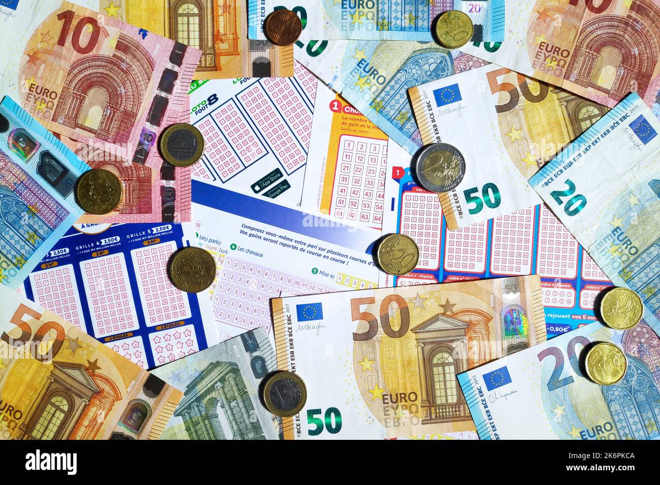 Paris, France - 21 septembre 2022 : quelques pièces et billets en euros au-dessus d'une pile de billets de loterie. Banque D'Images