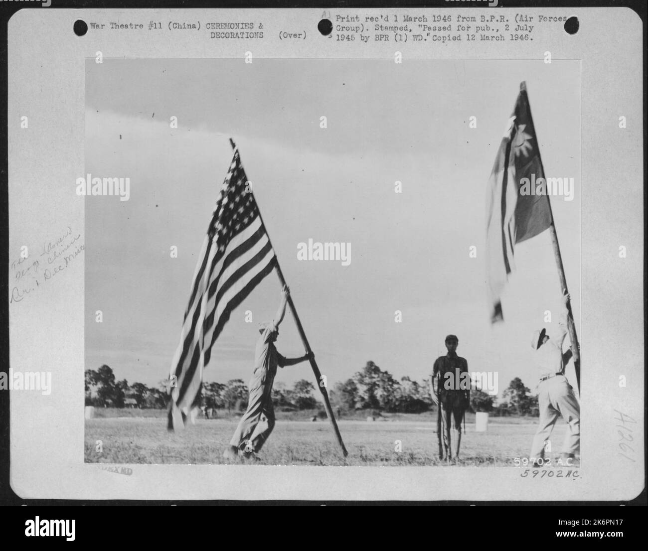 L'ancienne gloire et le drapeau de la Chine libre remonter à la base aérienne américaine de Nanning, Chine après sa réoccupation par l'AF 14th. Sergent Edward F. Rossler, à gauche, 2908, rue Vaughn, Cincinnati (Ohio) Hante le drapeau américain tandis Qu'Un interprète chinois local élève Banque D'Images