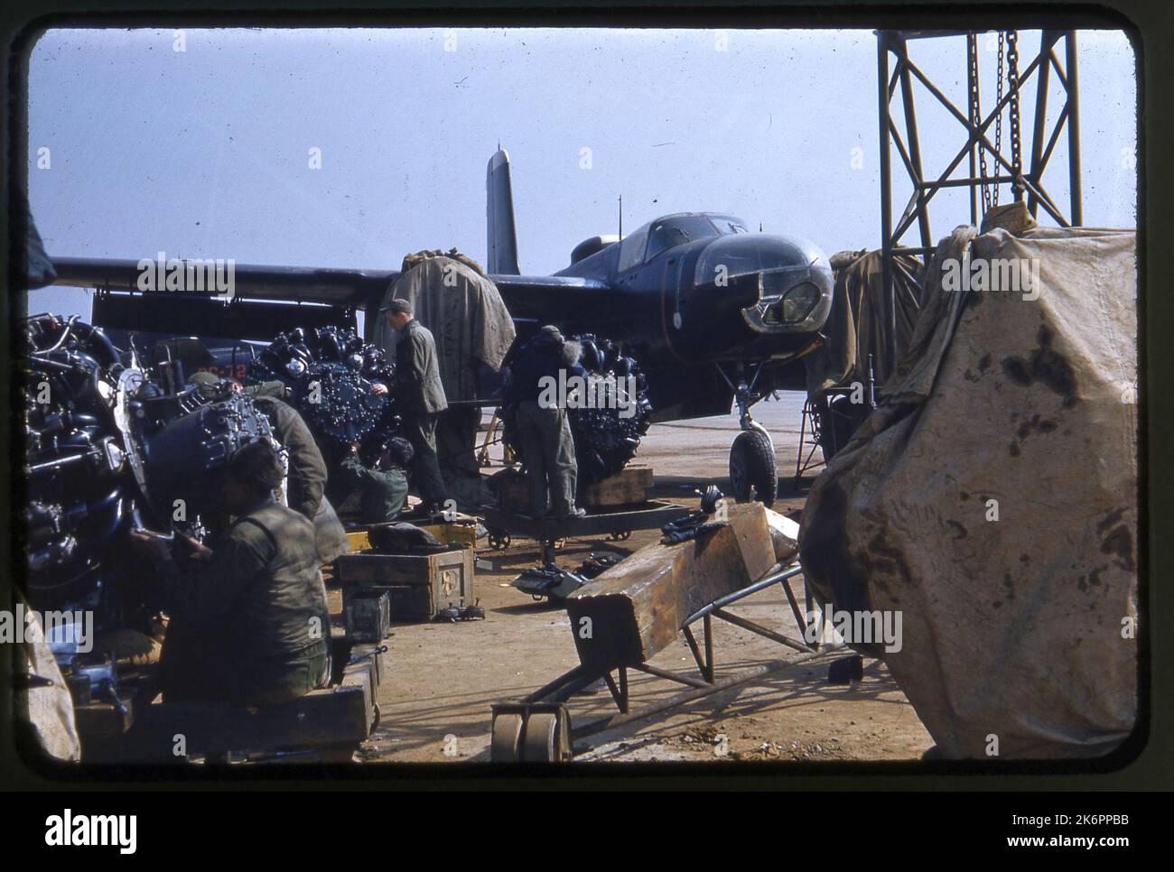 Vue de trois quarts avant droite d'un envahisseur Douglas RB-26C en arrière-plan, sans ses moteurs. Une zone de réparation de moteur, avec de nombreux moteurs et des ouvriers d'entretien est au premier plan. Vue de trois quarts avant droite d'un envahisseur Douglas RB-26C en arrière-plan, sans ses moteurs. Une zone de réparation de moteur, avec de nombreux moteurs et des ouvriers d'entretien est au premier plan. Banque D'Images