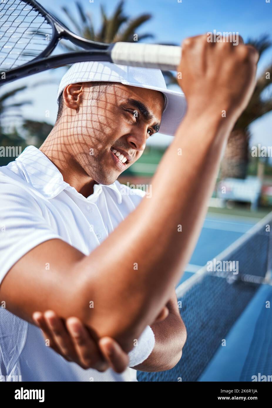 J'espère que ce n'est pas cassé. un beau jeune homme debout seul et souffrant d'une blessure au coude pendant une partie de tennis. Banque D'Images