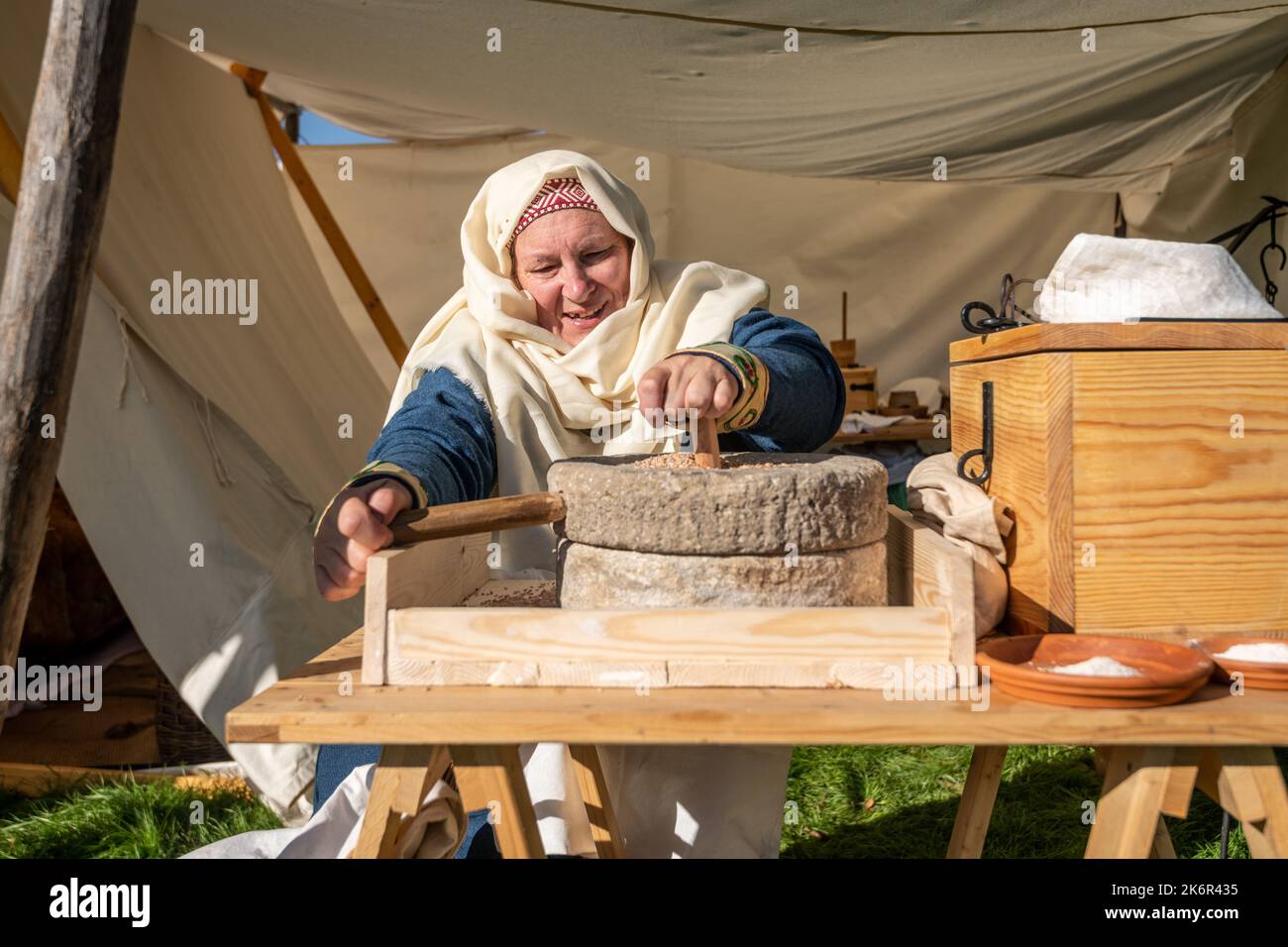 Une femme meule du blé pour la farine. Plusieurs répromulguer des socités prennent part à la bataille de Hastings, campé et vivant sur le terrain comme ils le feraient avant la guerre. Battle of Hastings, Battle, East Sussex, Grande-Bretagne. 15thoct 2022. Banque D'Images