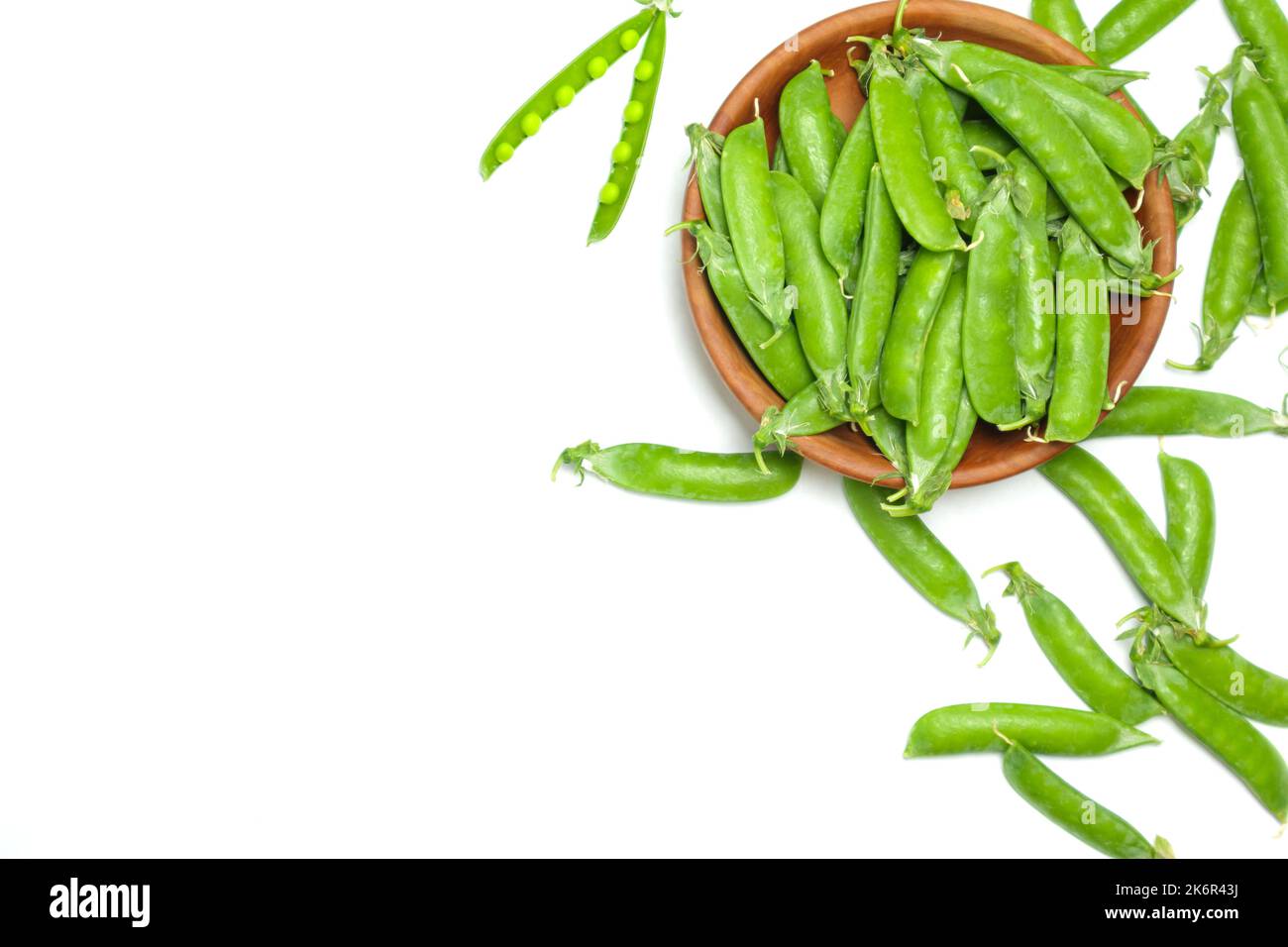 Petits pois verts frais avec gousse dans un bol isolé sur fond blanc. Banque D'Images