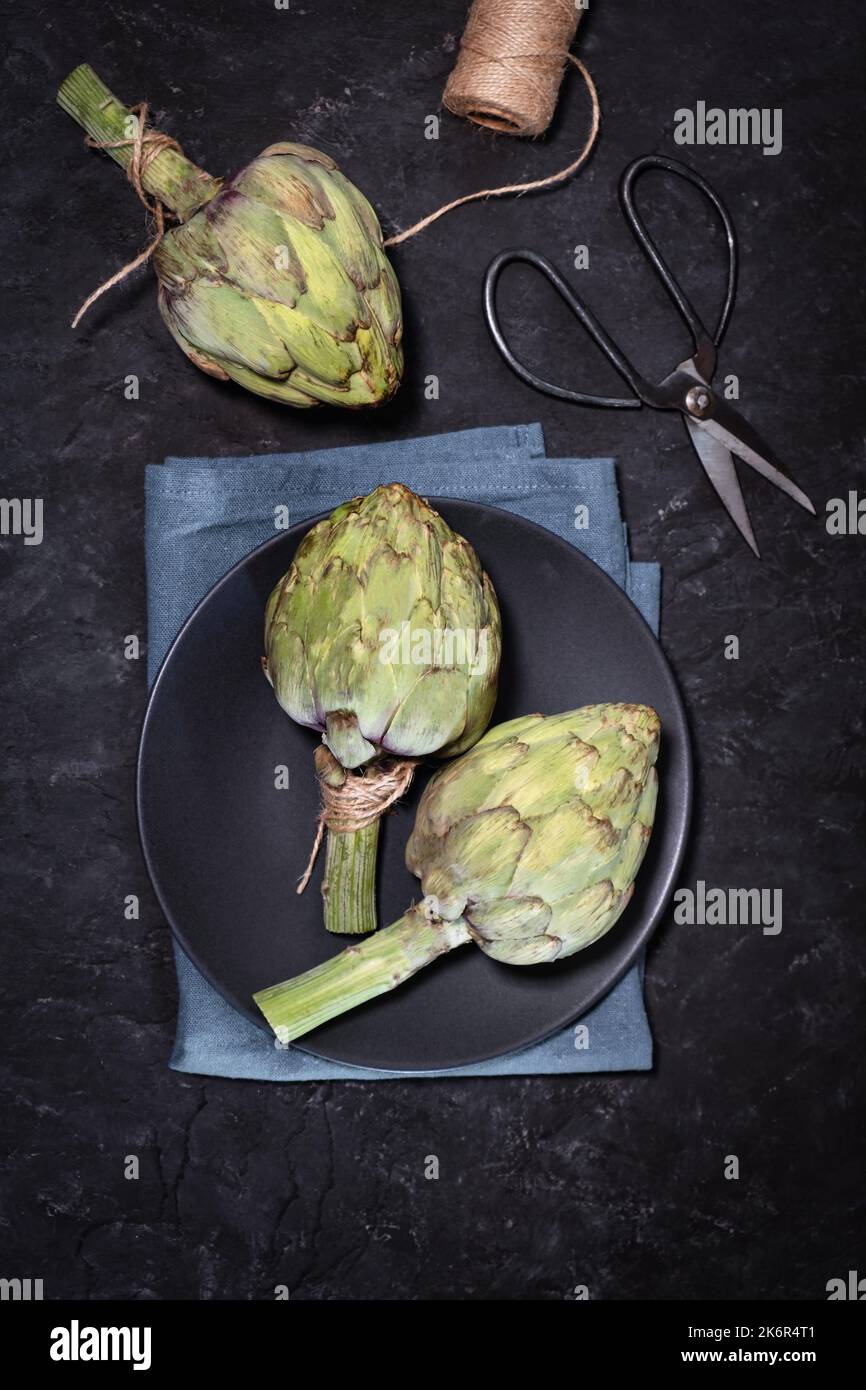 Artichauts violets non cuits sur fond noir Banque D'Images