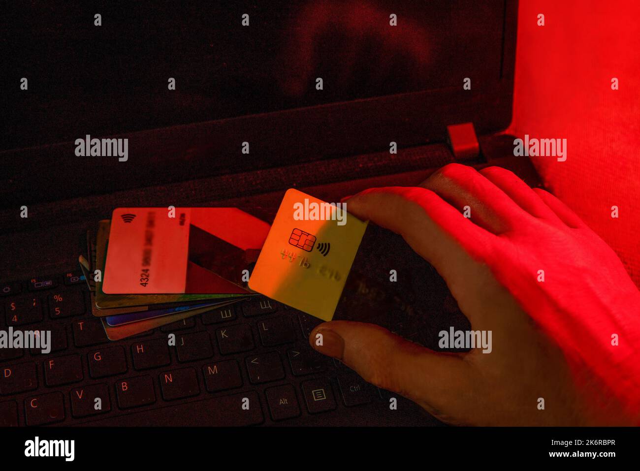 main rouge d'un voleur d'ordinateur (la lumière rouge représente l'effet du crime) qui vole d'une carte bancaire - temps sombre de la nuit (quand les choses sombres ha Banque D'Images