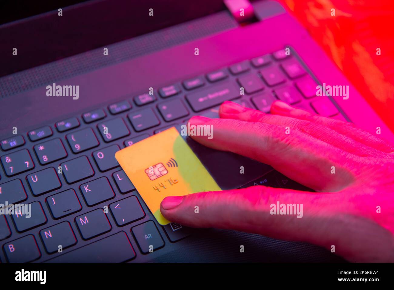 main rouge d'un voleur d'ordinateur (la lumière rouge représente l'effet du crime) qui vole d'une carte bancaire - temps sombre de la nuit (quand les choses sombres ha Banque D'Images