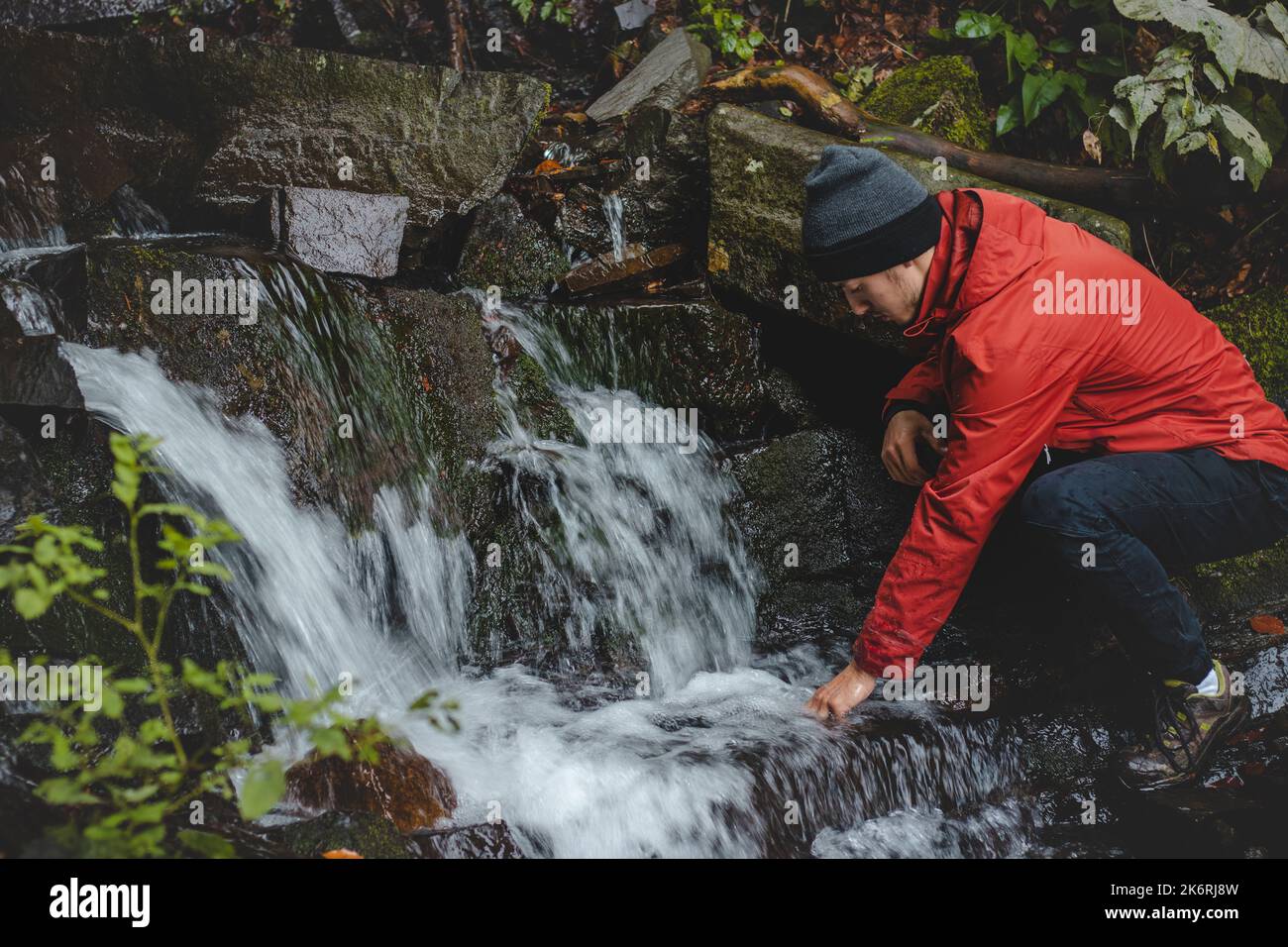 Randonneur sur une longue piste remplit l'eau potable d'une source de montagne dans un récipient en verre. Remplir d'eau propre pour cuisiner et boire tout en étant bien haut Banque D'Images