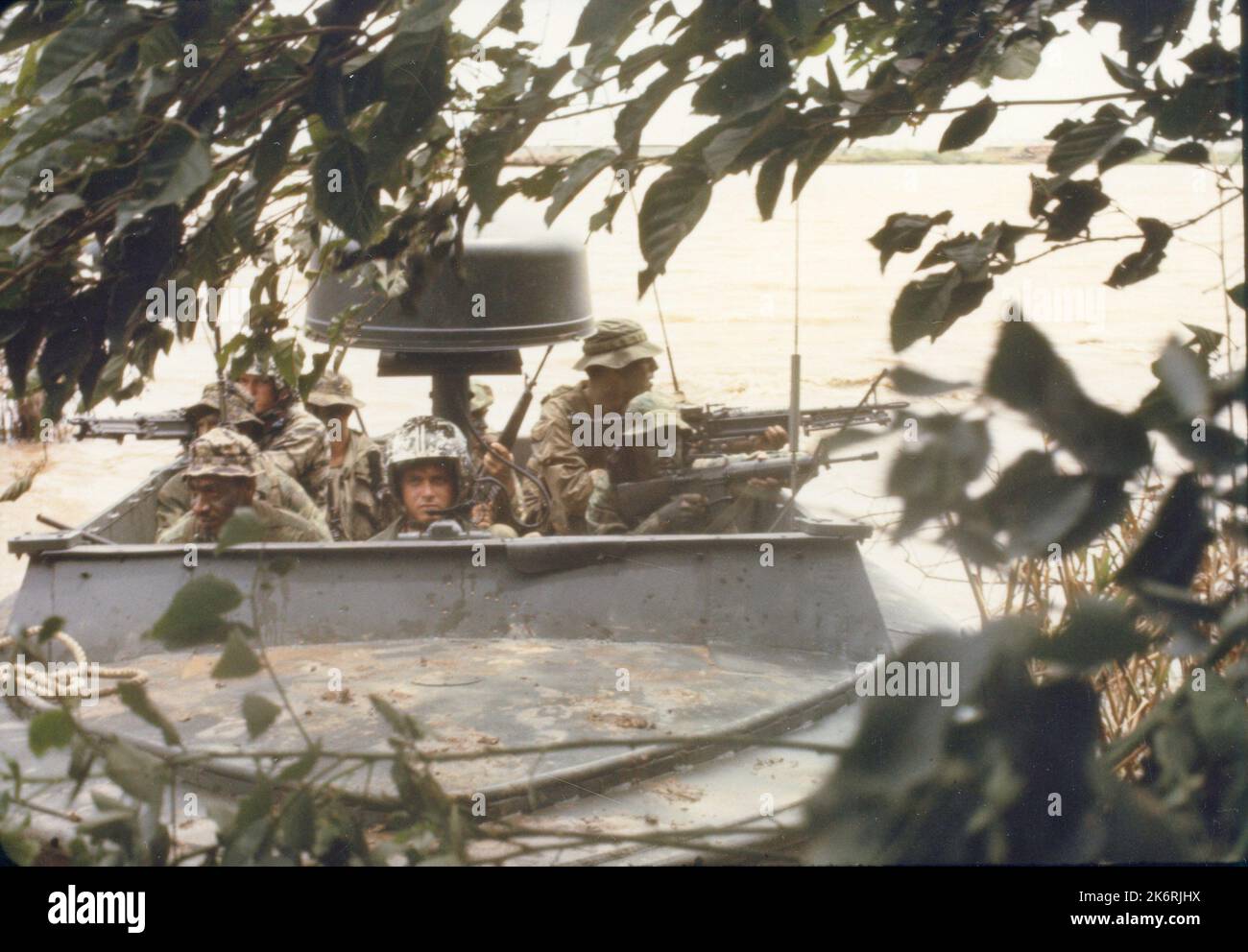Navy SEAL Team viennent à terre d'un River Patrol Boat'Vietnam ... membres d'un américain L'équipe Marine Sea-Air-Land (SEAL) s'est préparée à venir à terre à partir d'un bateau de patrouille fluviale (PBR) sur un site d'opération.'. Banque D'Images