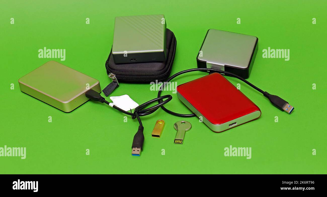 Disques durs externes à mémoire numérique et disques compacts sur fond vert Banque D'Images