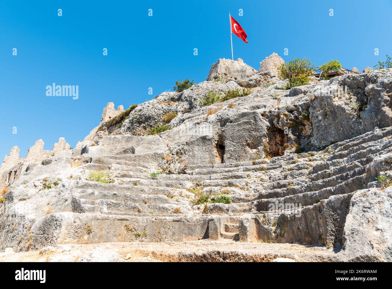 Petit amphithéâtre ancien dans le château Simena en ruines dans le village de Kalekoy dans la région de Kekova dans la province d'Antalya, Turquie. Vue avec un drapeau turc agitant. Banque D'Images