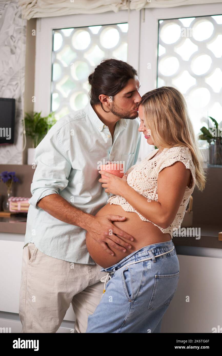 Portrait vertical doux d'un couple enceinte caucasien qui attend bébé à la maison confortablement. Banque D'Images