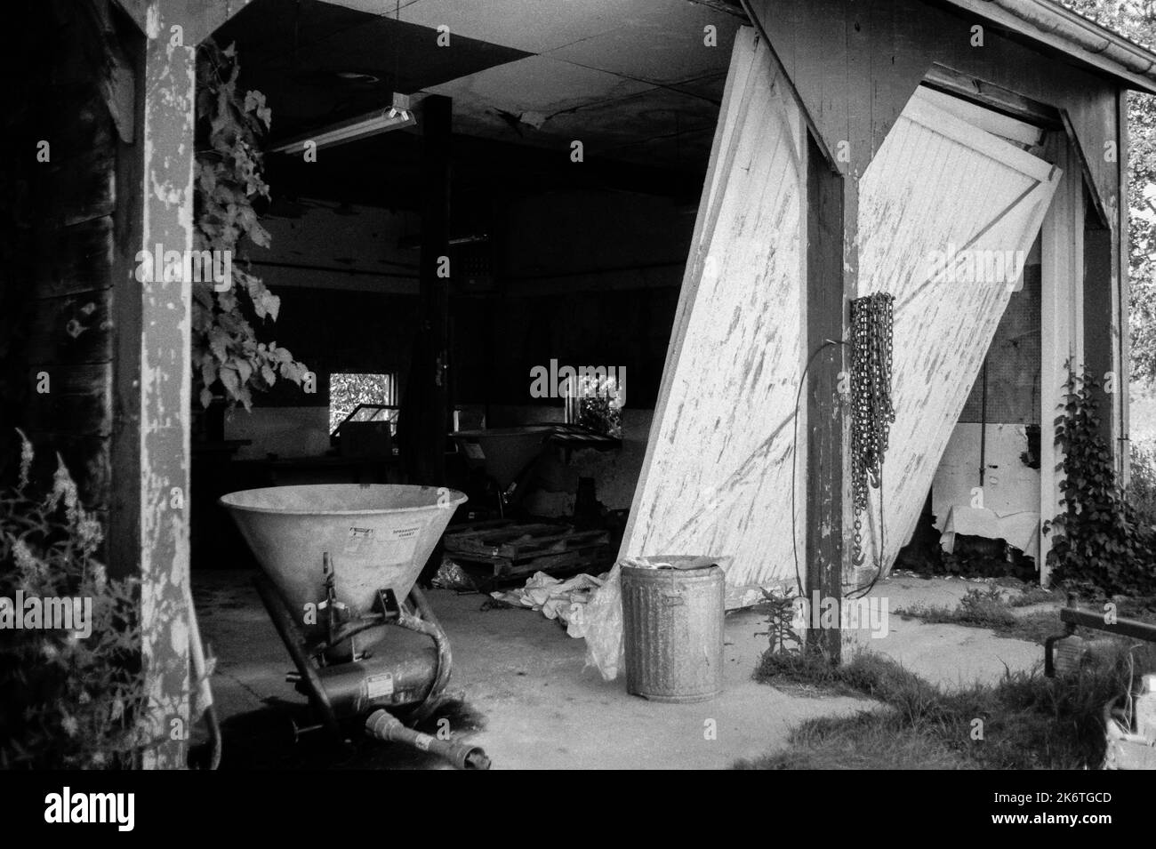 Une cale chancelante dans un grand garage avec des portes cassées et de l'équipement de construction laissé derrière à Cogswell Grant dans l'historique Essex, Massachusetts. T Banque D'Images