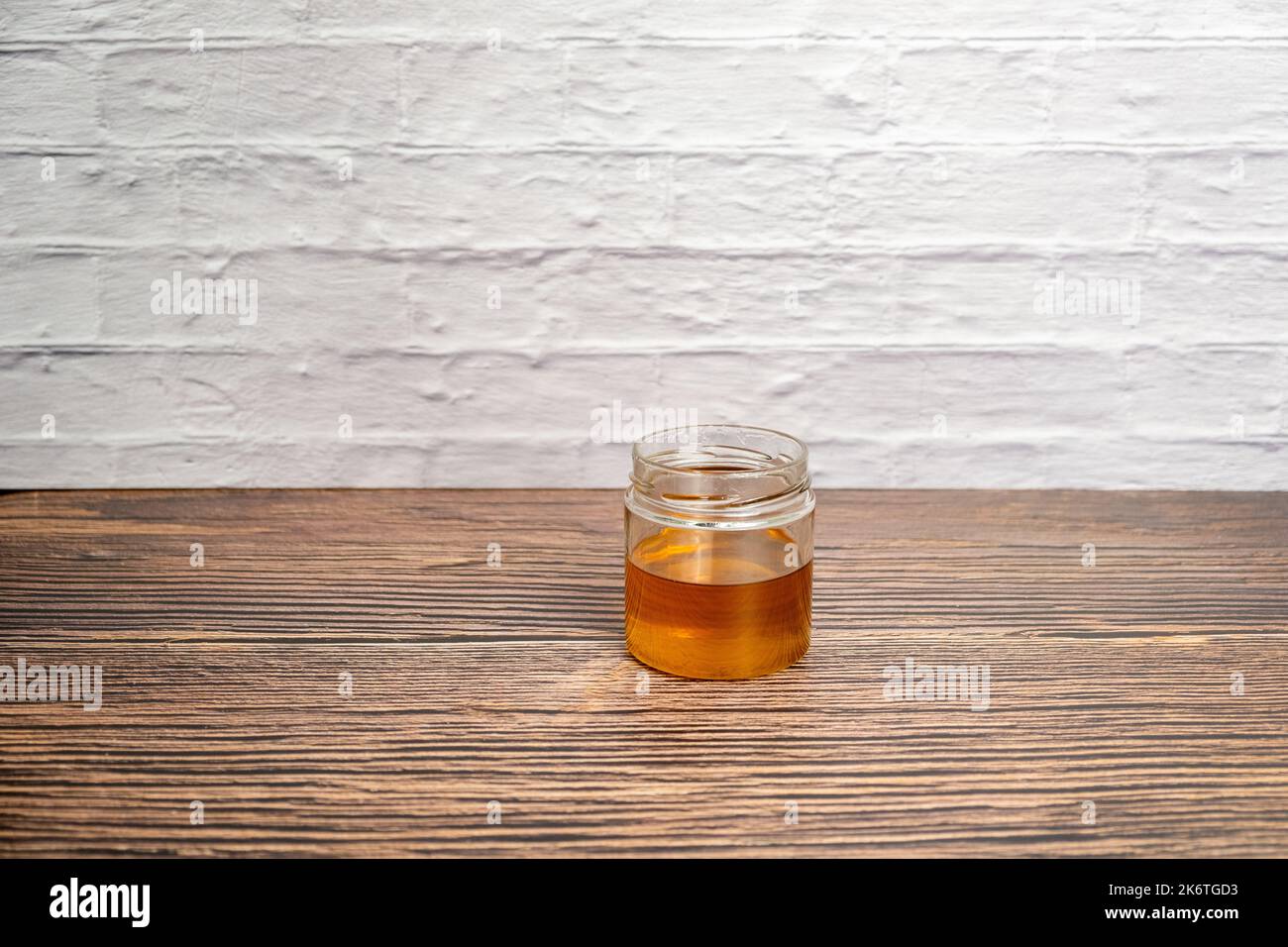Pot de miel isolé sur un mur en bois et en brique blanche Banque D'Images