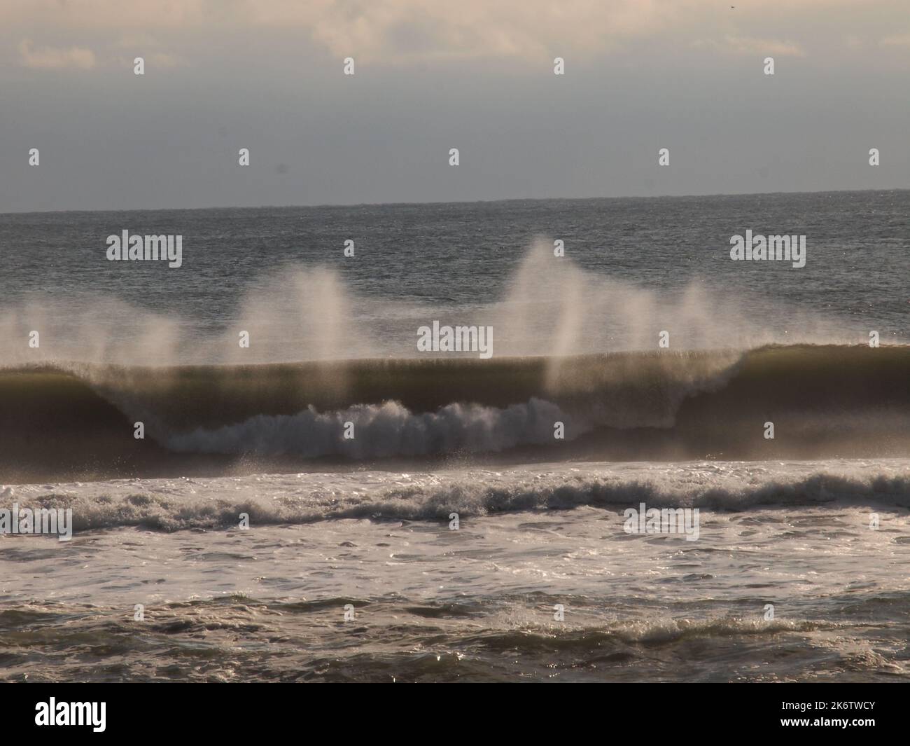 La tempête a lancé des vagues qui se sont écrasées contre la côte du New Jersey et le vent a soufflé sur leurs sommets. Rétroéclairées, les courbes apparaissent transparentes. Banque D'Images