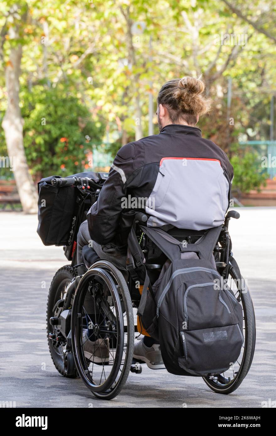 Jeune personne handicapée sur un fauteuil roulant électrique voyageant avec ses bagages.technologie moderne pour les handicapés. Banque D'Images