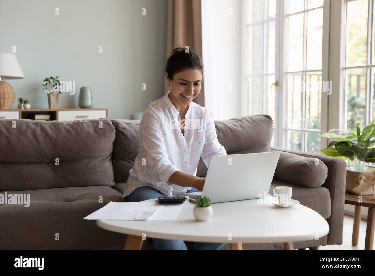 Femme indienne souriante qui paie des factures via l'application de banque électronique utilise un ordinateur portable Banque D'Images