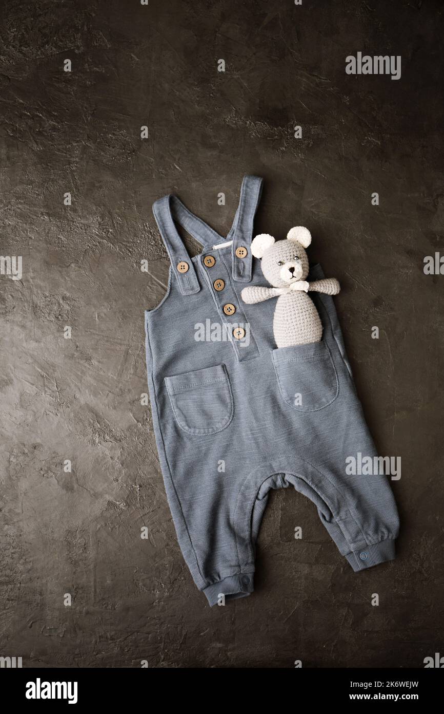 pantalon gris avec un ours en peluche tricoté pour un nouveau-né sur fond gris Banque D'Images