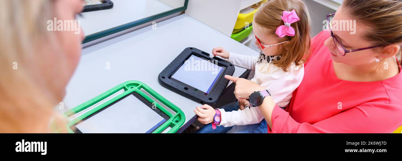 Fille non verbale vivant avec une paralysie cérébrale, apprenant à utiliser une tablette numérique pour communiquer. Les gens qui ont de la difficulté à développer la langue ou nous Banque D'Images