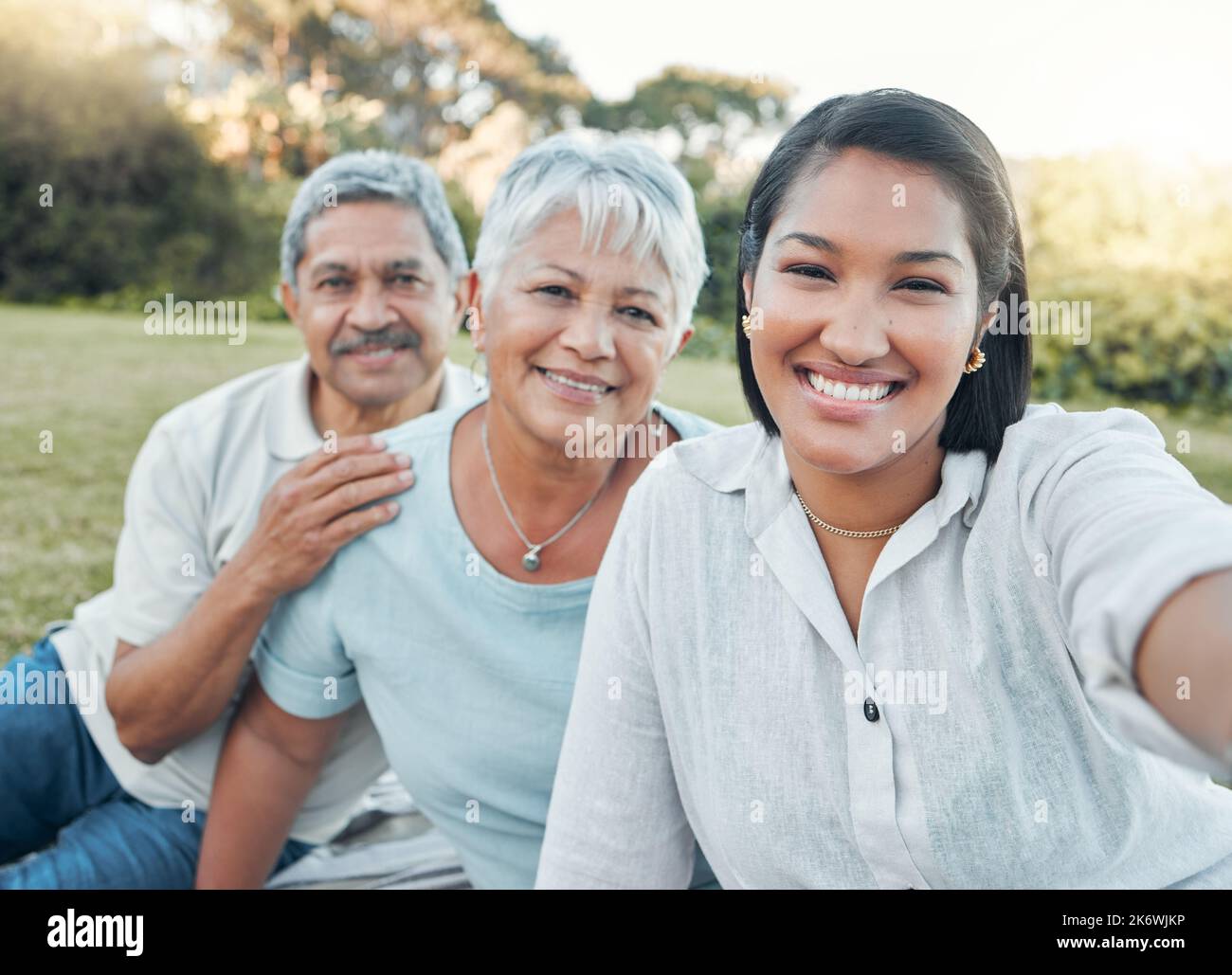 Faire partie d'une famille signifie sourire pour les photos. une femme qui prend un selfie avec ses parents dans un parc. Banque D'Images