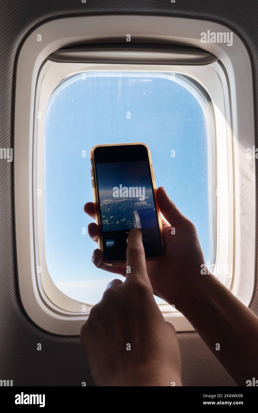 Un passager prend des photos avec son smartphone en avion et regarde la vue depuis la fenêtre. . Photo de haute qualité Banque D'Images