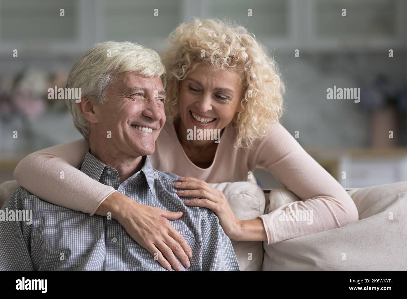 Une femme souriante plus âgée enrasse son mari joyeux et bien-aimé Banque D'Images