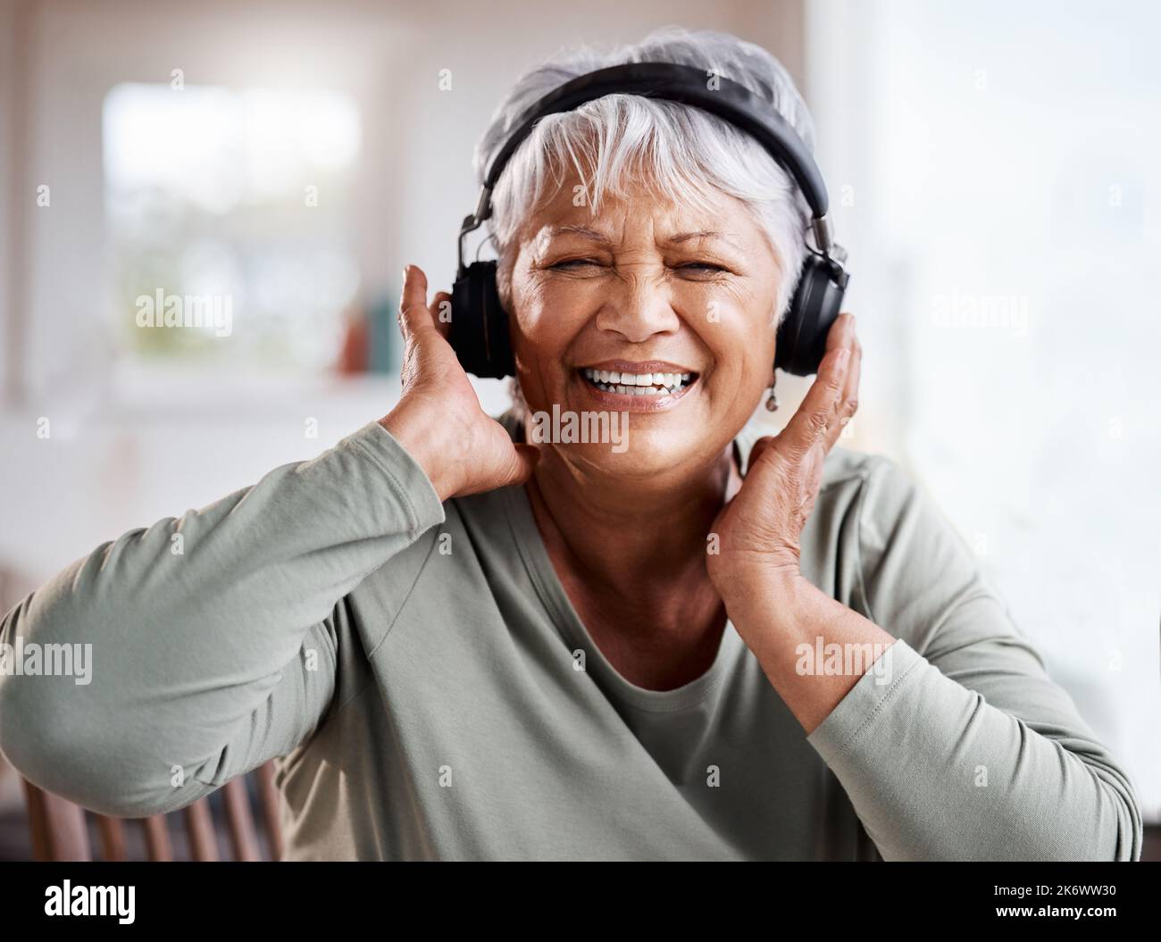 Vivez et laissez vivre. une belle femme âgée qui écoute de la musique tout en étant assise sur le canapé à la maison. Banque D'Images