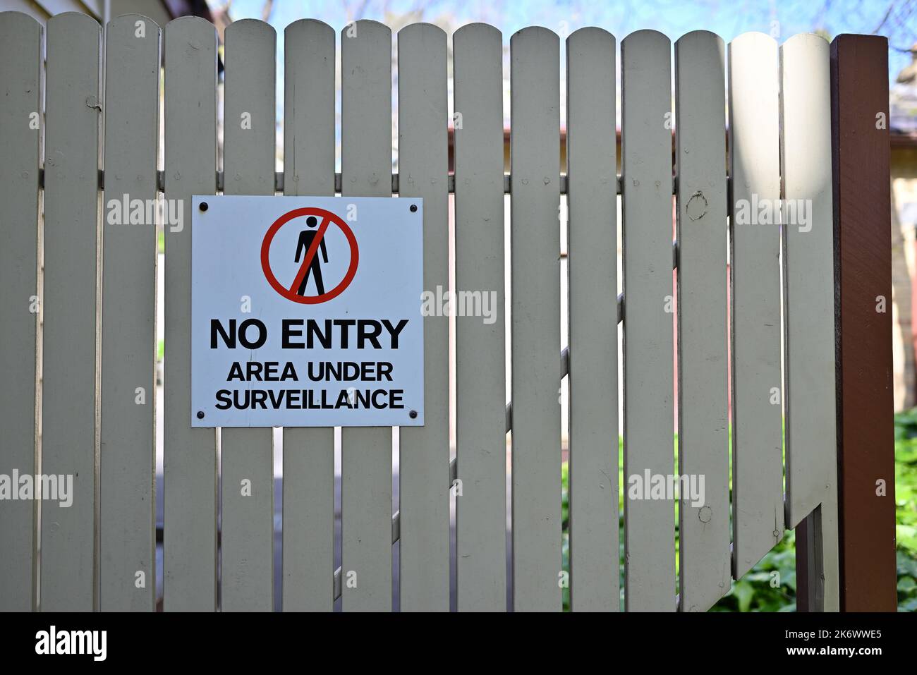 Zone d'interdiction d'entrée blanche, rouge et noire sous le panneau de surveillance sur une porte en bois de couleur crème, à l'ombre pendant une journée ensoleillée Banque D'Images