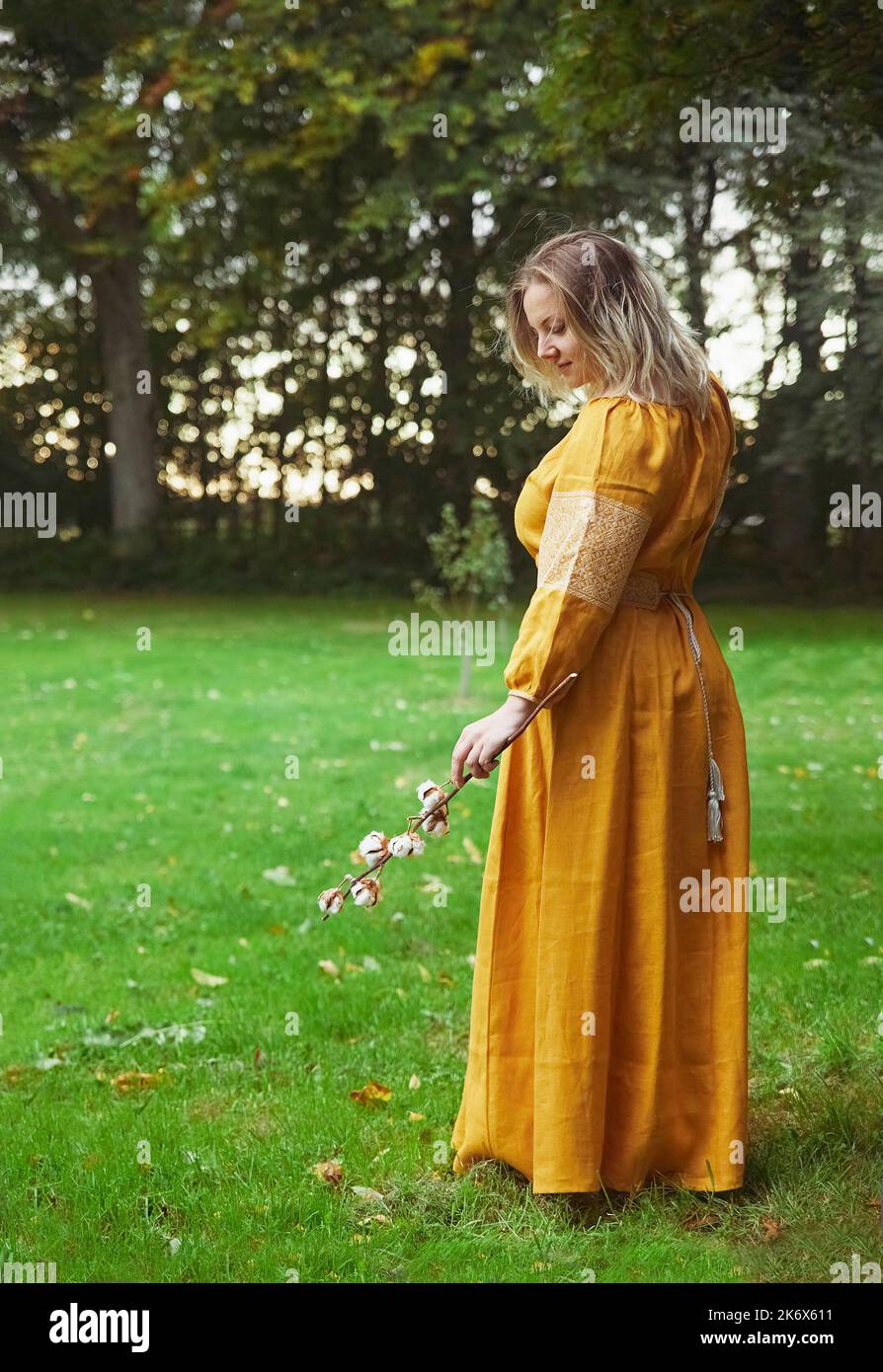Belle femme ukrainienne en robe brodée tient une branche de coton Banque D'Images