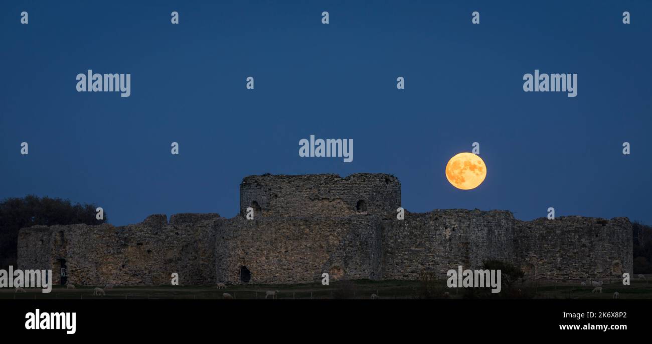 Octobre les chasseurs pleine lune se dressent derrière les ruines du château de Camber près de Rye est Sussex sud-est de l'Angleterre Banque D'Images