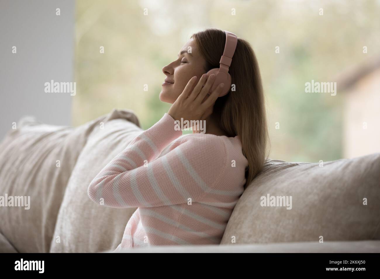 Une jeune femme dans un casque écoute votre chanson préférée à la maison Banque D'Images