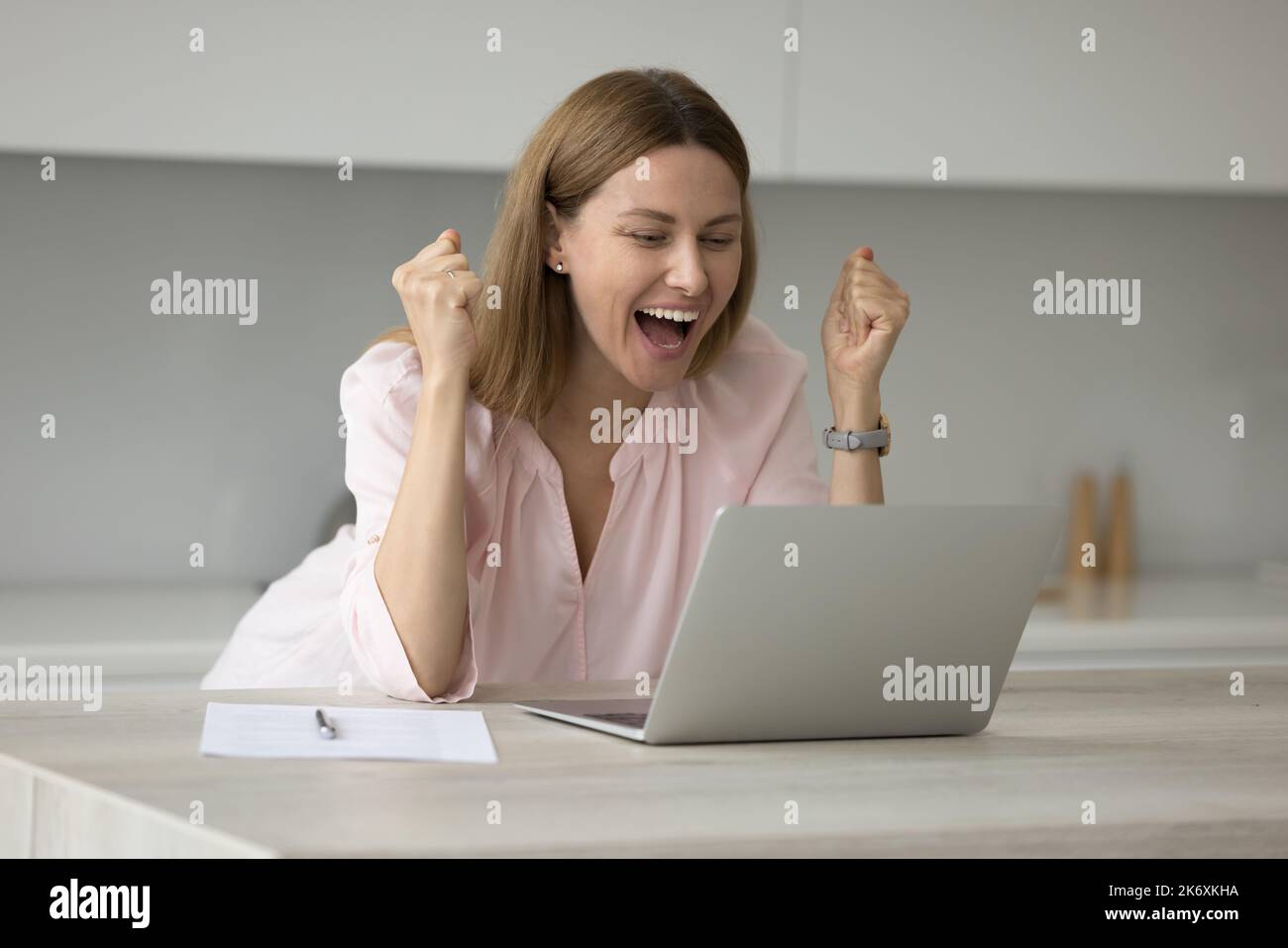 Une femme regarde le PC portable crier avec joie tout en lisant les nouvelles Banque D'Images