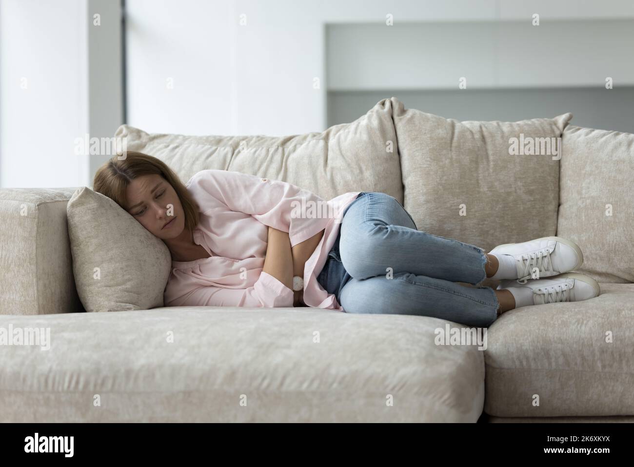 Une jeune femme triste et malheureuse souffre de douleurs physiques ou mentales Banque D'Images