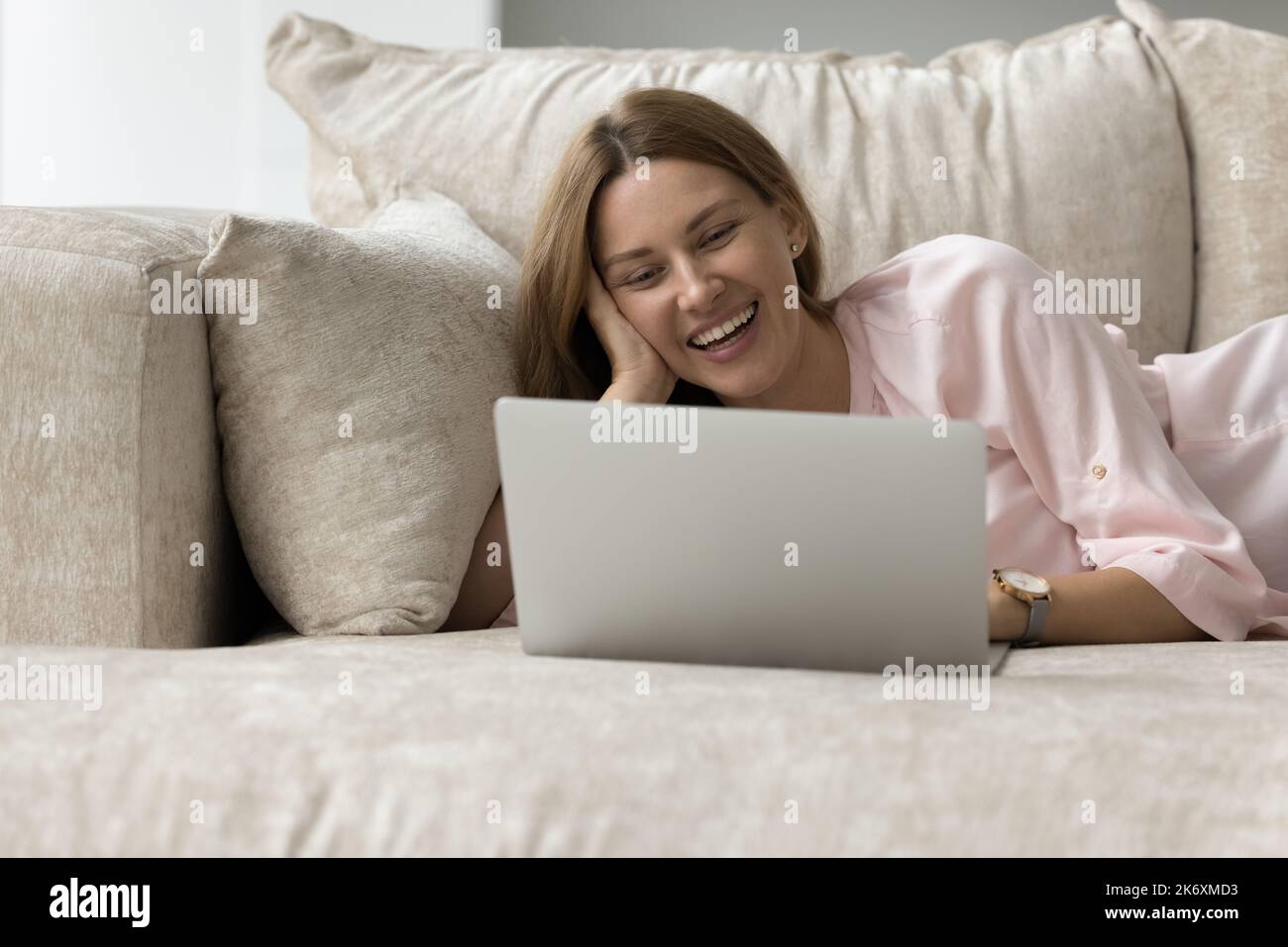 Une femme heureuse aime l'utilisation d'Internet sur un canapé avec ordinateur portable Banque D'Images