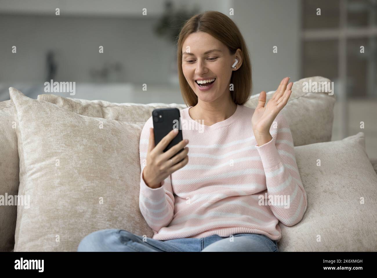 Femme souriante porter des écouteurs sans fil Profitez des appels vidéo utiliser un téléphone portable Banque D'Images