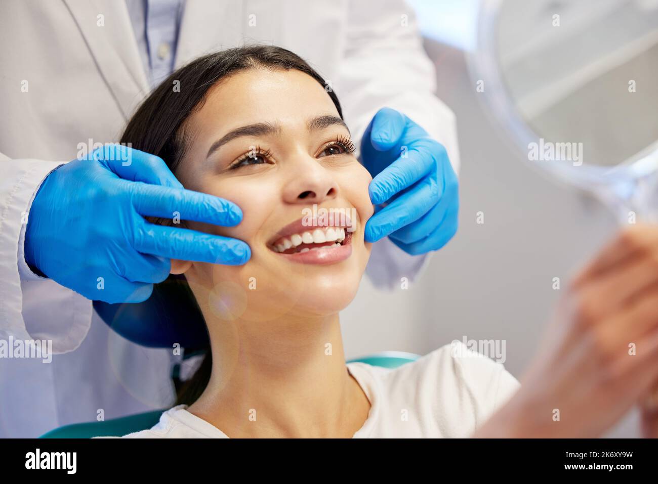 Merci doc, je les aime. une jeune femme admirant ses dents après avoir fait une procédure dentaire. Banque D'Images