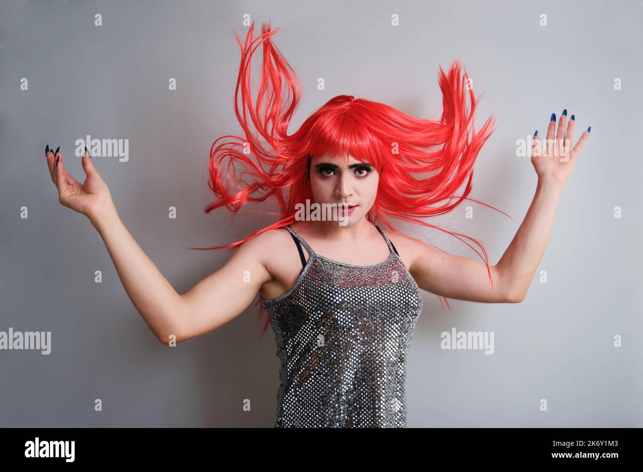 Portrait d'une reine de drag portant une perruque rouge et regardant l'appareil photo. Banque D'Images