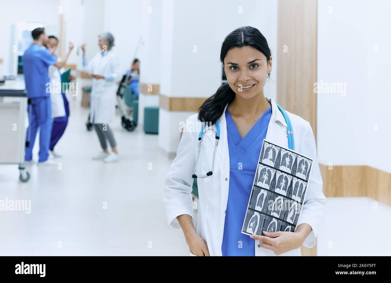 Pulmonologieist asiatique amical avec scanner CT des poumons humains portant un uniforme médical avec stéthoscope debout dans le couloir de l'hôpital. Technologie d'acquisition CT Banque D'Images