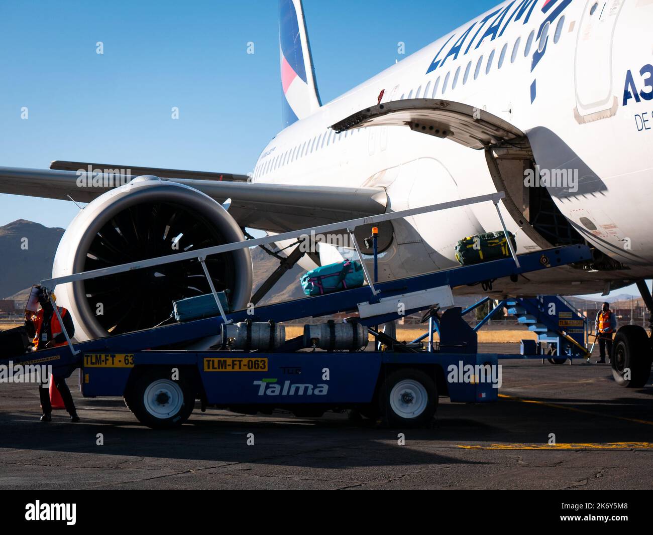 Juliaca, Pérou - 27 juillet 2022 : courroie transporteuse qui transporte les bagages d'une petite porte de l'avion à une petite voiture pour livrer les bagages à l'intérieur Banque D'Images