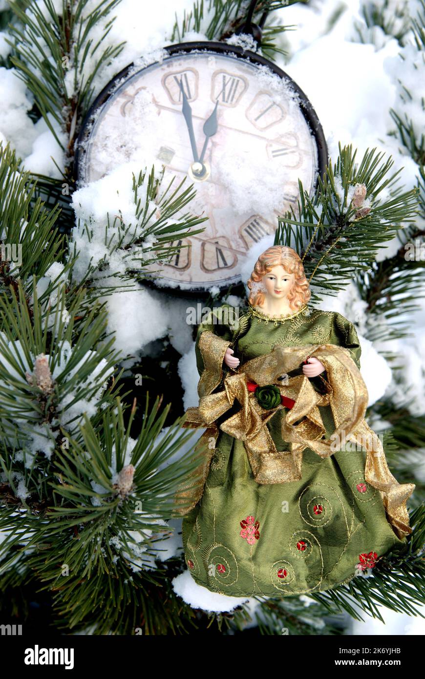 Horloge de Noël et poupée sur le fond de l'arbre de noël recouvert de neige Banque D'Images