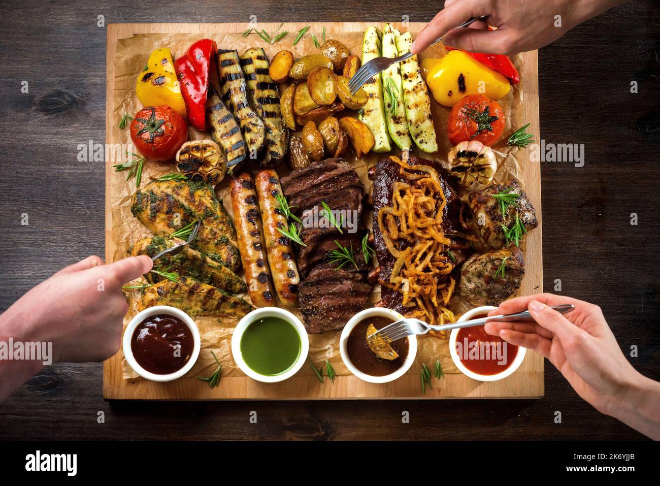 Un tableau avec des hors-d'œuvre grillés et des sauces. Légumes grillés et en-cas de viande : saucisses, filets de poulet, steaks de porc et de bœuf. Banque D'Images