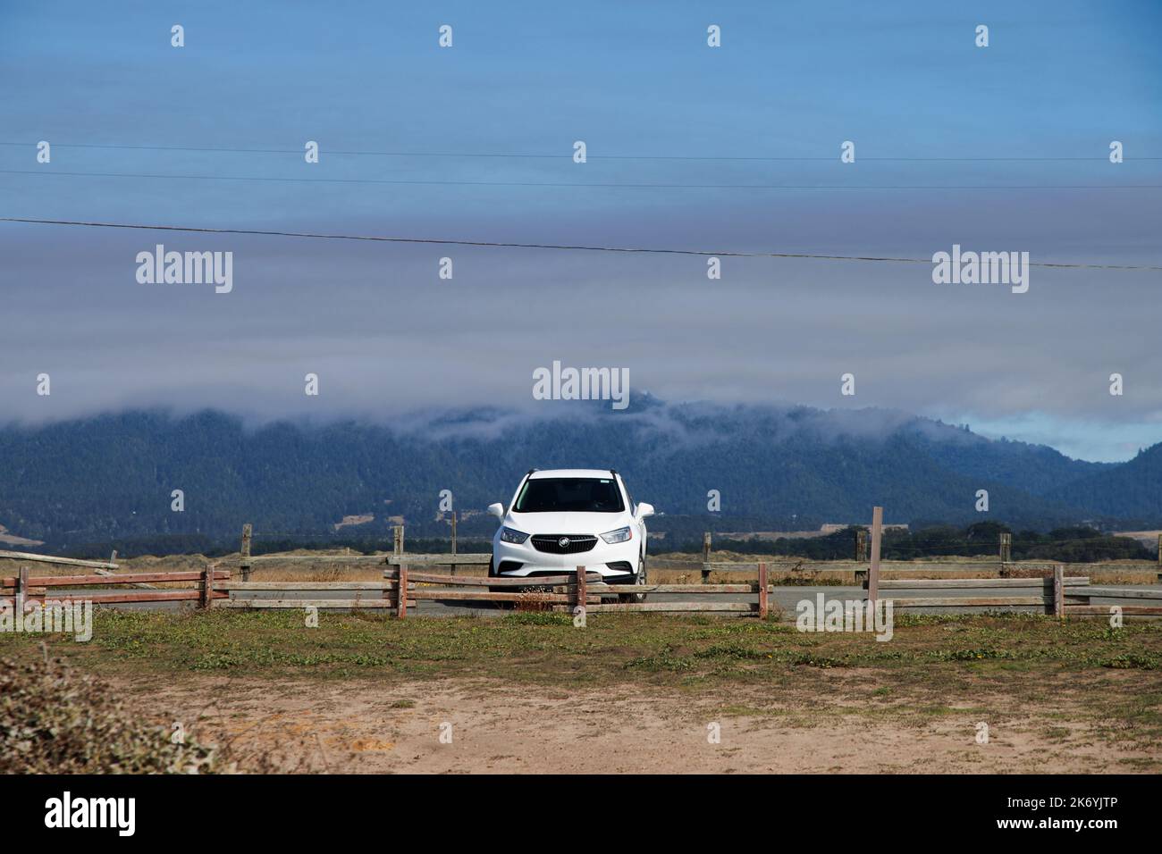 Voyage sur la route américaine - voiture blanche devant les montagnes couvertes de nuages Banque D'Images