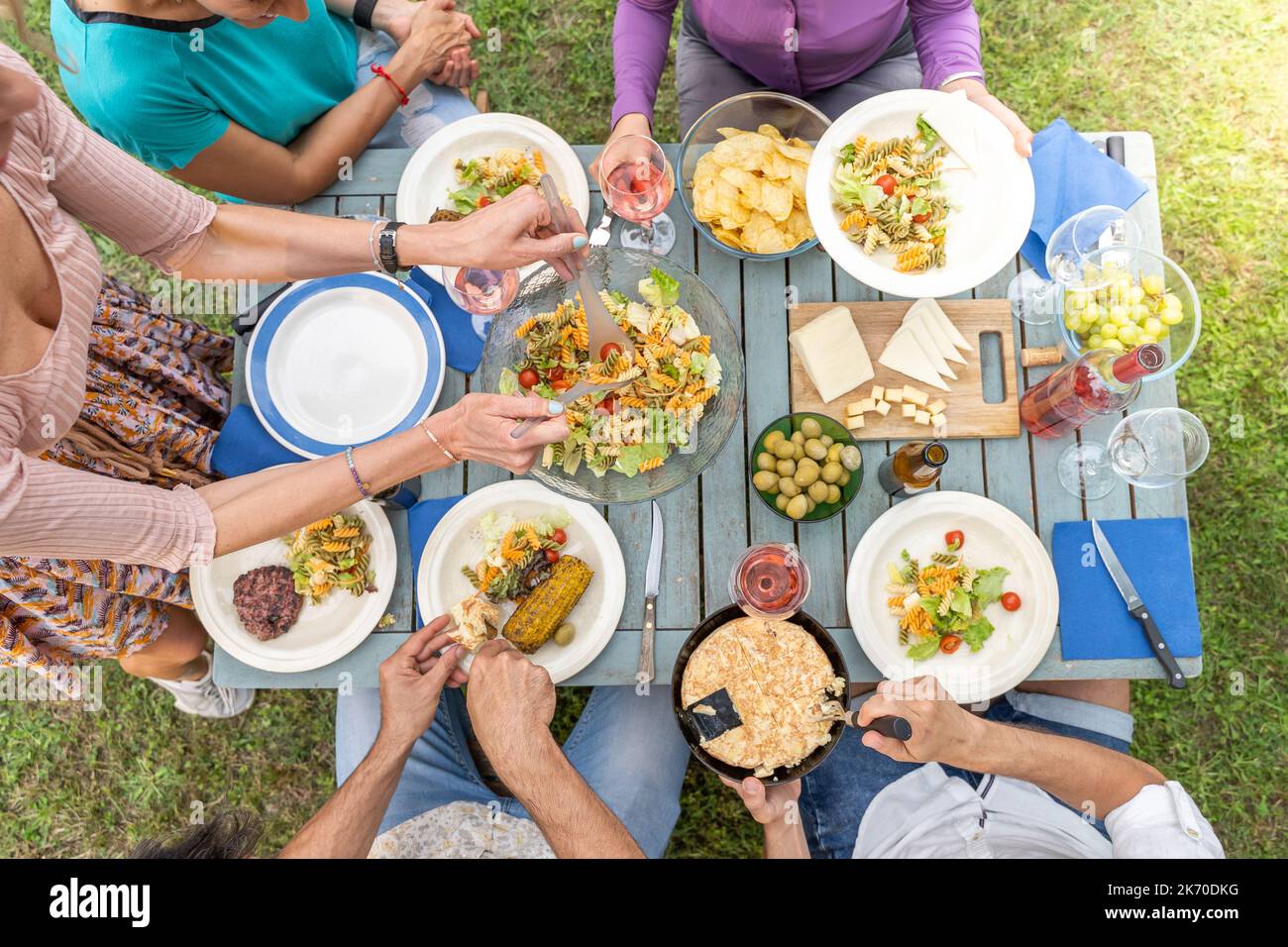 Amis multiculturels assis à une table en bois. Amis qui dînent. Ils ont des assiettes pleines de nourriture et des verres avec des boissons. Banque D'Images