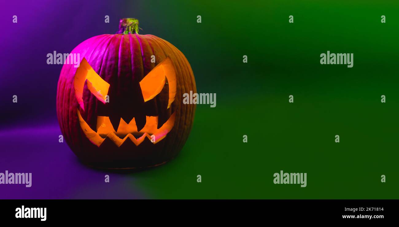 Véritable Halloween orange citrouille violet et vert bannière de fond donnant des vibes effrayantes de saison. Portrait effrayant de la tête de citrouille illuminant à l'intérieur avec orange li Banque D'Images