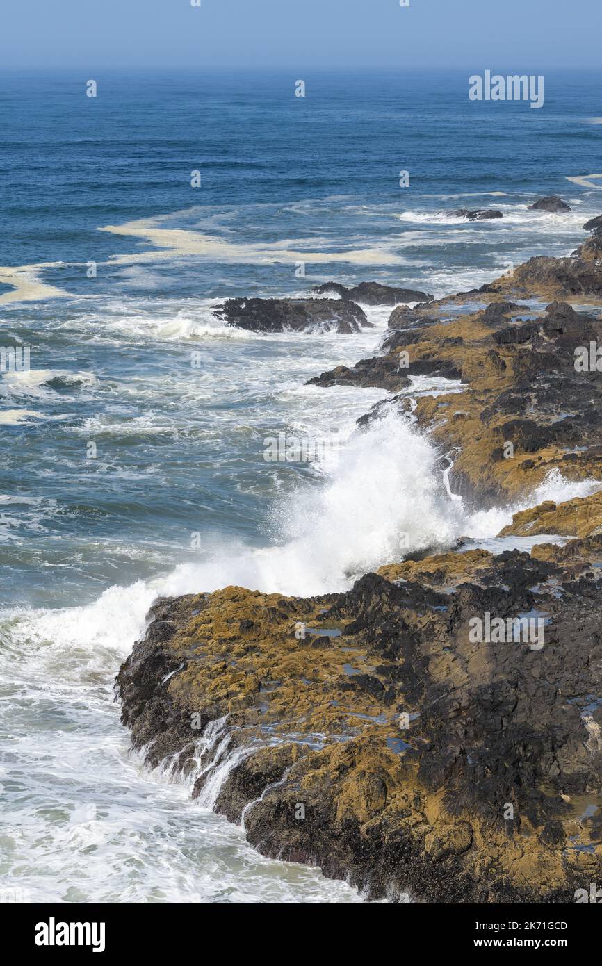 Des vagues se sont écraées à terre de l'océan Pacifique sur la côte de l'Oregon avec un océan bleu et un ciel et des rochers colorés Banque D'Images