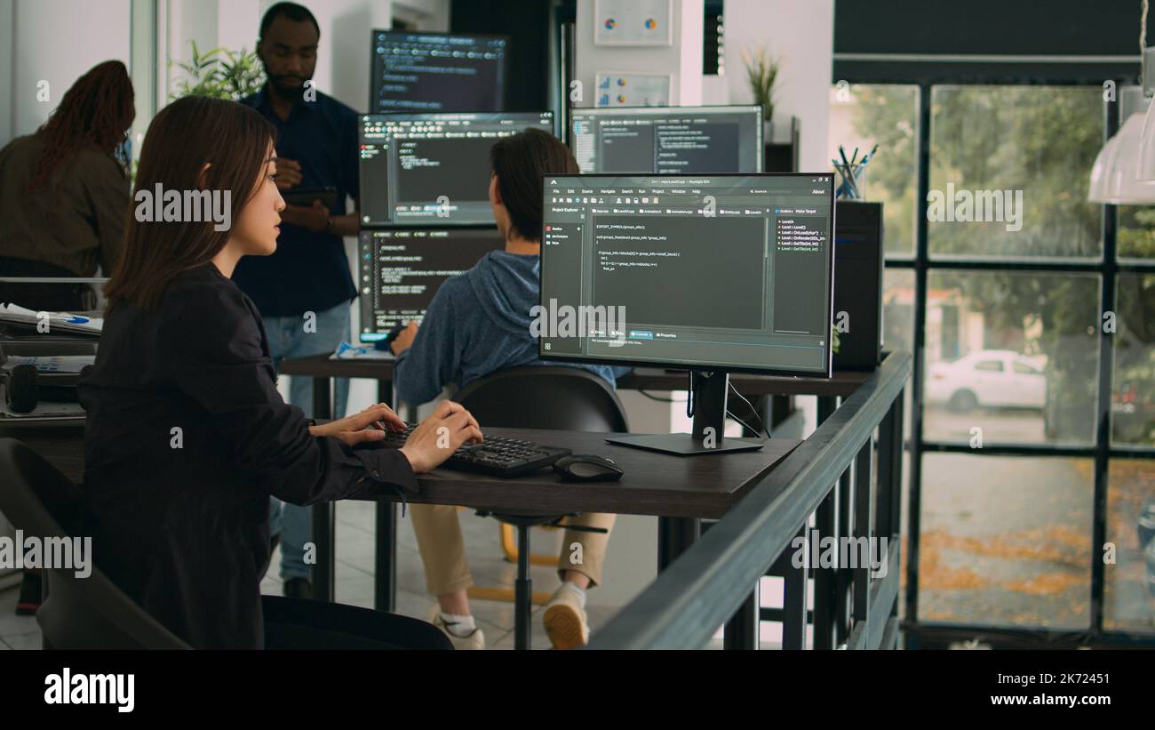 Ingénieur logiciel asiatique travaillant avec l'interface utilisateur sur l'écran de l'ordinateur pour développer un nouveau pare-feu de sécurité et un script html. Le programme de base de données écrit du code avec des algorithmes de serveur dans la fenêtre de terminal. Banque D'Images