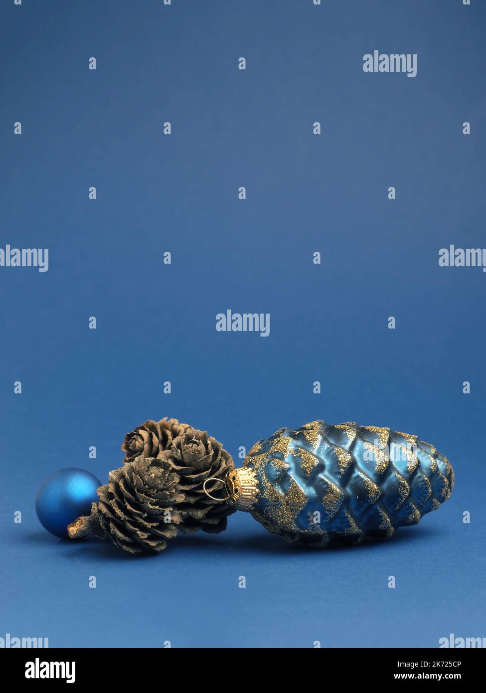 Boule de Noël bleue avec des cônes de pin sur fond bleu avec espace pour votre texte ou votre image Banque D'Images