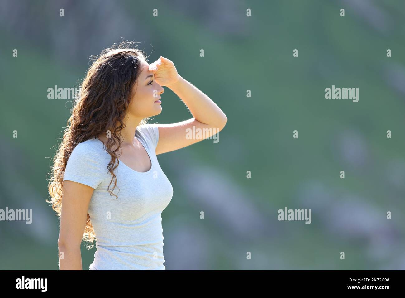 Profil d'une femme recherchant avec la main sur le front dans la montagne Banque D'Images