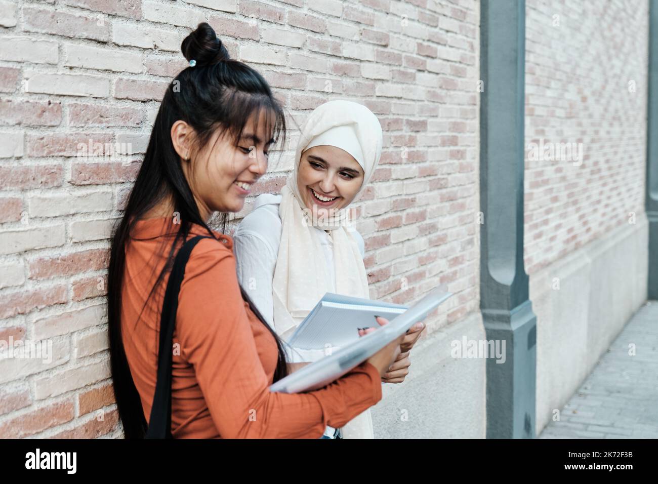 Des amies multi-ethniques souriant tout en étudiant ensemble à l'extérieur. Banque D'Images